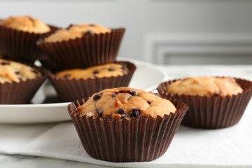 Delicious muffin with chocolate chips on table, closeup