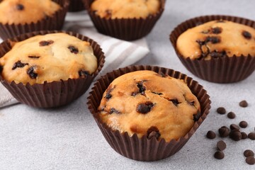 Delicious muffin with chocolate chips on light grey table, closeup