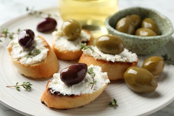Delicious sandwiches with cream cheese and marinated olives on light table