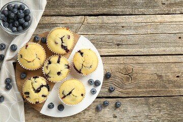 Delicious muffins with blueberries on wooden table, flat lay. Space for text