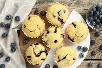 Delicious muffins with blueberries on wooden table, flat lay