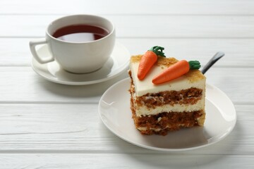 Piece of delicious homemade carrot cake with tea on white wooden table