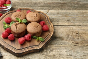 Delicious muffins with raspberries and mint on wooden table. Space for text