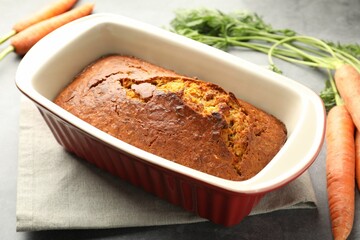 Tasty carrot cake and vegetables on grey textured table, closeup