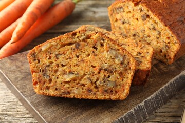 Homemade carrot cake with nuts and vegetables on wooden table, closeup