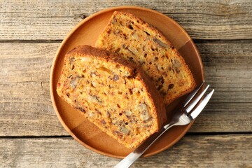 Pieces of homemade carrot cake with nuts and fork on wooden table, top view
