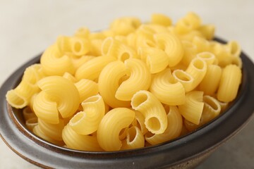 Raw horns pasta in bowl on gray table, closeup