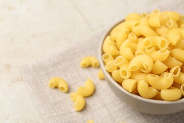 Raw horns pasta in bowl on gray table, closeup. Space for text