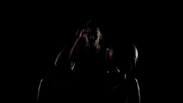 Basketball player sitting on a bench praying. Religious african american sports man against black background.