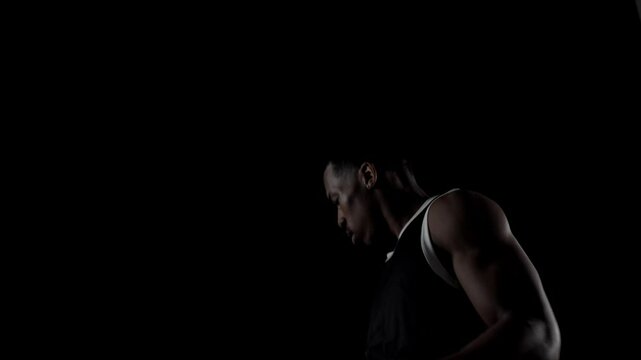 Basketball player spinning a ball. African american sports man practicing against black background.