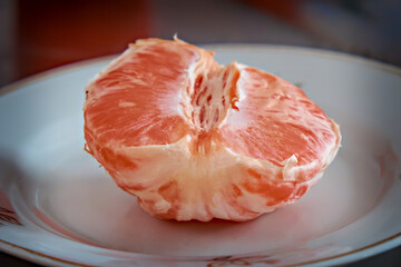 Half of peeled grapefruit on a plate. Selective focus. Close-up