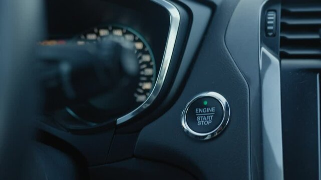 Close-up of finger pressing push start button in modern car to start engine. Keyless ignition system in modern vehicle