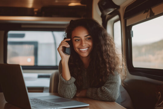 Young Woman Working Remotely Inside an RV Smiling Digital Nomad Talking on Cell Phone Cozy Motorhome Home Office Lifestyle High-Resolution Stock Photo
