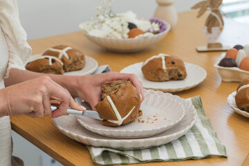 A woman a Hot Cross Bun at the festive table. Happy Easter.