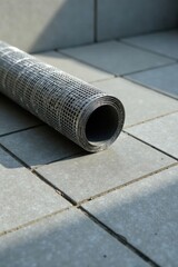 Rolled reinforcing mesh resting on a paved surface, ready for construction or repair projects