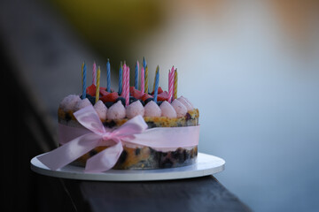 A beautifully decorated birthday cake features colorful candles and fresh fruit, resting on a...