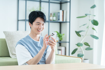 リビングでスマホを使う若い男性