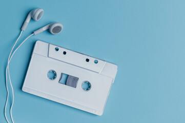 Wired headphones with audio tape on a blue background. Retro style,