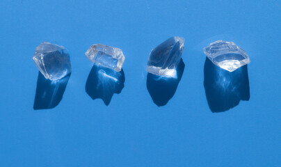Ice cubes with water drops on light blue background,hard light with shadows