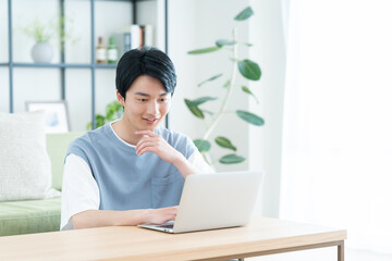 リビングでパソコンを見る若い男性