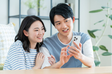 リビングでスマホを見る若い夫婦