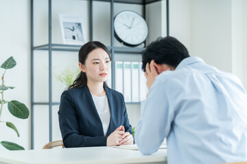 Obraz premium 悩む若い男性の相談にのるプランナーの女性