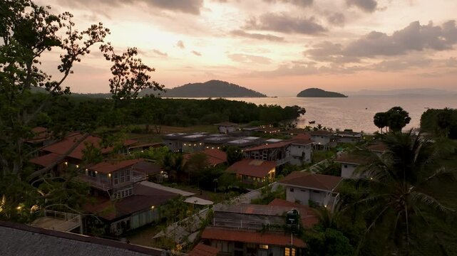 Tropical beachfront villas overlooking a turquoise bay surrounded by lush green hills and calm sea waters. Koh Yao Yai, Thailand