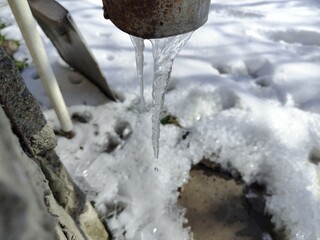 Icicle hangs under a drainpipe of a house