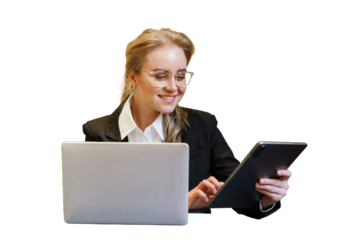 Business professional working on tablet while sitting at desk with laptop in modern office setting