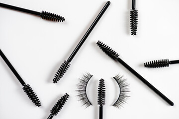 Scattered eyelash and brow makeup brushes with false eyelashes on white background. Women beauty and eye makeup.