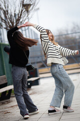 Obraz premium Two young women joyfully dancing together outdoors in a casual urban setting