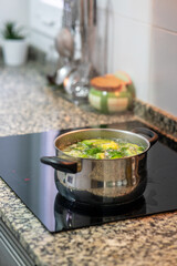 Pot cooking vegetables on modern induction cooker in domestic kitchen