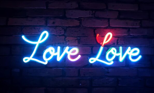Colorful neon signs displaying the word love on a rustic brick wall at night