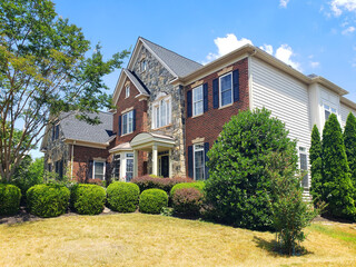 Fragment of a two-story modern house with brick trim. The house has traditional architectural...