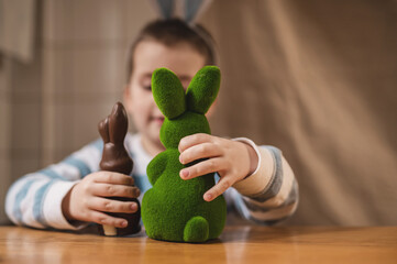 Boy with bunny ears 5 years old playing with Easter bunnies at table close-up, defocused image....
