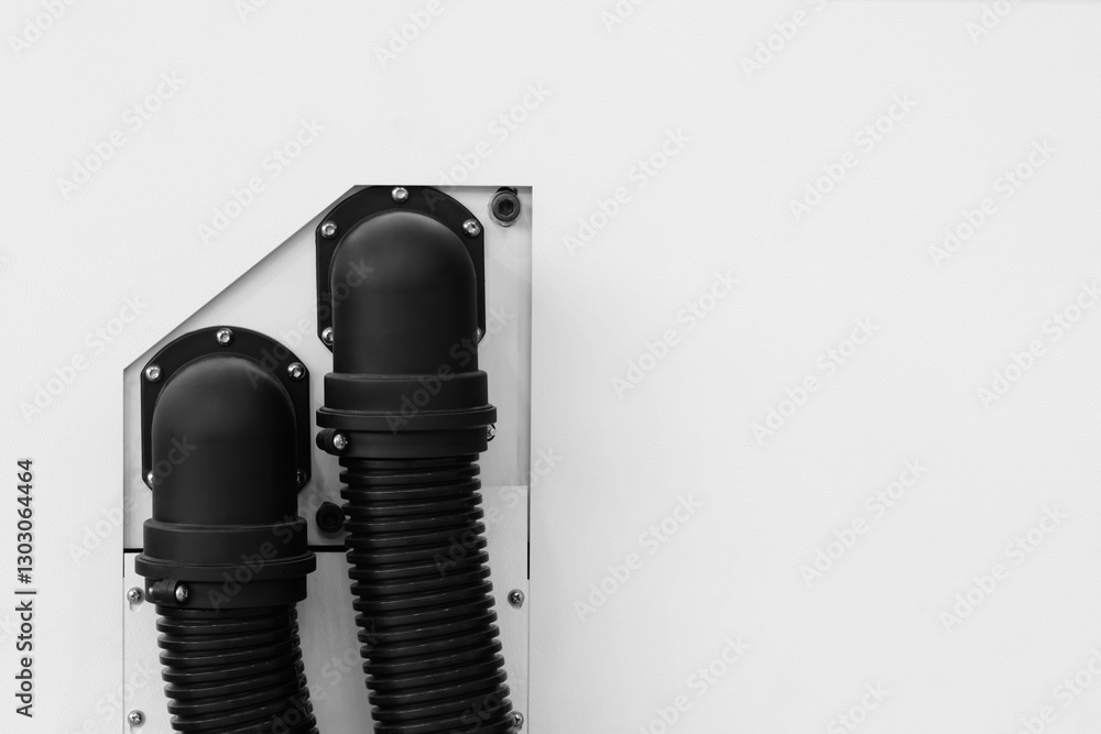 Poster two black pipes are attached to a white wall. the pipes are connected to a white object. industrial 