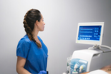 Nurse monitoring patient vital signs on medical equipment