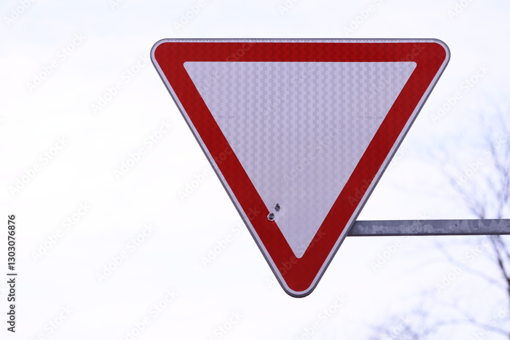 Aufkleber A red and white warning sign on a pole with a triangular shape, used to indicate caution or alertness.