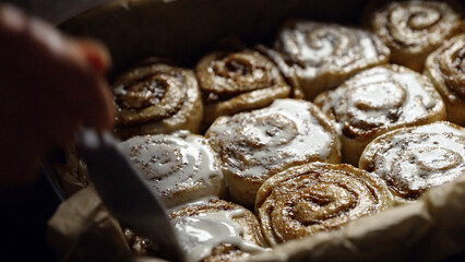 The cinnamon rolls are brushed with cream using a brush.