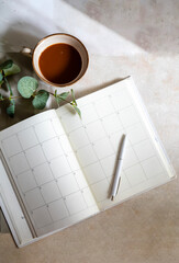 Planner notebook and cup of coffee on shadows background 