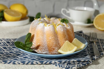 Delicious cake with lemon zest, powdered sugar and mint on light textured table, closeup