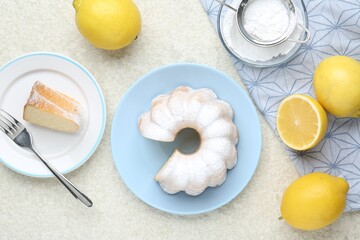 Delicious lemon cake with powdered sugar and citrus fruits on light textured table, flat lay