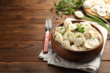 Delicious dumplings served on wooden table, space for text