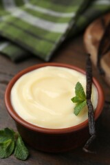 Tasty vanilla pudding, mint and pod on wooden table, closeup