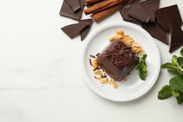 Tasty chocolate pudding with peanuts and mint on white table, flat lay. Space for text