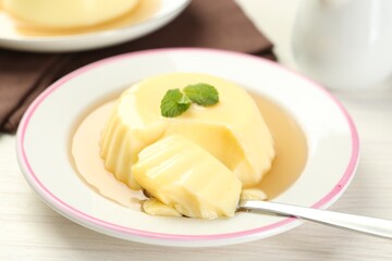 Delicious pudding with caramel sauce and mint served on white table, closeup