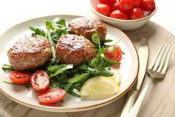 Delicious patties with greens, tomatoes and cutlery on table, closeup