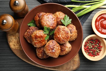 Delicious patties and spices on black textured table, flat lay