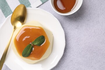 Delicious pudding with caramel sauce and mint served on light table, flat lay. Space for text