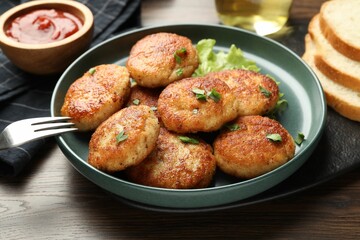 Delicious patties, parsley, lettuce, ketchup and fork on wooden table, closeup
